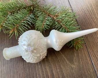 Puede incluir: Adorno de árbol de Navidad de vidrio blanco con un diseño de copo de nieve y detalles de purpurina.