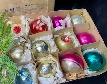 May include: A box of vintage Christmas ornaments, including silver, gold, pink, red, and blue ornaments with various designs. The box is labeled "HABIB No 1."