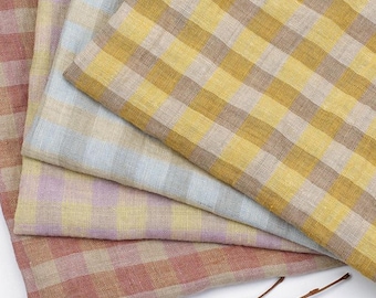 May include: A stack of four linen napkins in a variety of colors. The napkins feature a checkered pattern in shades of red, yellow, and blue. The fabric has a soft, textured appearance, and the napkins are neatly folded.