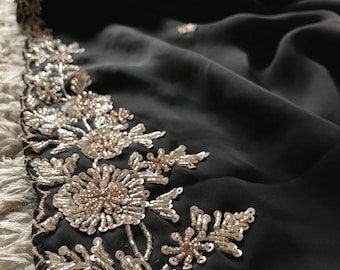 May include: Black fabric with a silver and gold beaded floral design. The beads are arranged in a pattern of flowers and leaves.