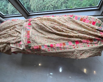 May include: A cream-colored fabric shawl with a floral pattern and a colorful embroidered border. The border features pink, red, orange, blue, and green accents.
