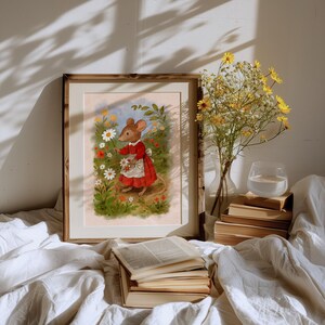 May include: A framed art print featuring a whimsical illustration of a mouse in a red dress and white apron, picking flowers in a garden. The artwork is set against a soft, pastel background, framed in a wooden frame. A vase of yellow flowers and a stack of books are also visible.
