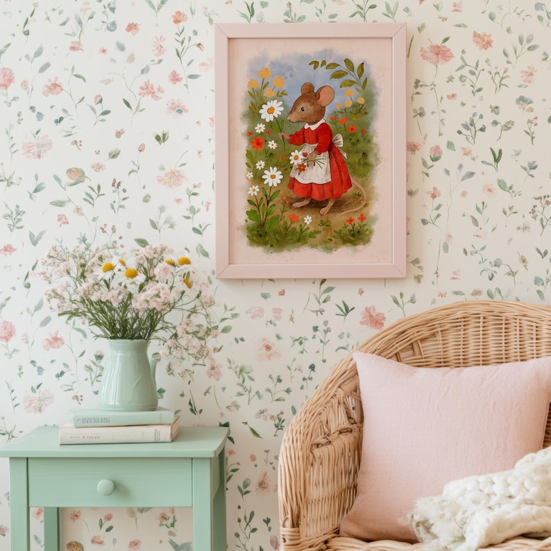 May include: A framed illustration of a mouse in a red dress picking flowers. The artwork is in a pink frame and hangs on a floral wallpaper. A vase of flowers sits on a mint green side table. A wicker chair with a pink pillow is in the foreground.
