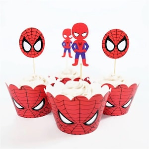 Puede incluir: Tres envoltorios de cupcake rojos y blancos con un diseño de Spiderman. Cada envoltorio tiene un cupcake blanco dentro. Hay tres adornos de Spiderman, uno con una cara de Spiderman y dos con figuras de Spiderman.