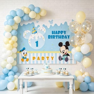 May include: A birthday party setup featuring a blue and white backdrop with Mickey Mouse and Donald Duck graphics, text reading Happy Birthday Party, a tiered cake, and balloon arches in shades of light blue, white, and pale yellow.