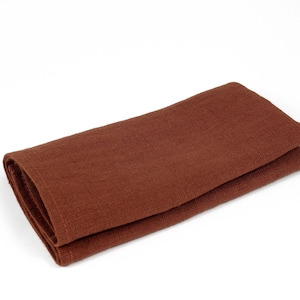 May include: A folded brown linen napkin. The napkin is made of a soft, textured fabric.