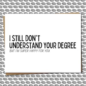 May include: A greeting card with the text "I STILL DON'T UNDERSTAND YOUR DEGREE BUT I'M SUPER HAPPY FOR YOU" in black font. The card is white with a brown border and a gray brain pattern background.