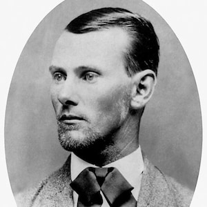 May include: Black and white portrait photograph of a man with short, dark hair, wearing a collared shirt and a bow tie. The photo is in an oval frame.