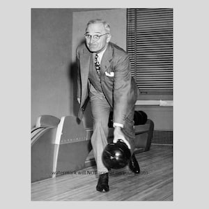 May include: A black and white photograph of a man in a suit bowling. He is wearing a suit jacket, a waistcoat, a tie, and a pocket square. He is holding a bowling ball in his right hand and is about to release it.