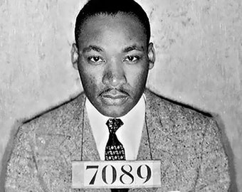 May include: A black and white photo of a man in a suit and tie. He is wearing a name tag that says "7089".