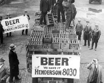 May include: Black and white photo of a delivery truck loaded with crates of beer. The truck has a sign that reads "Beer Gull Henderson 8030".
