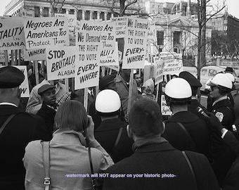 May include: Black and white photo of a protest in front of a building. People are holding signs that read "Stop Brutality in Alabama", "Negroes Are Americans Too", and "We Demand the Right to Vote Everywhere".