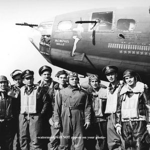 Peut inclure: Photographie en noir et blanc d'un groupe d'aviateurs devant un bombardier B-17. L'avion est marqué "MEMPHIS BELLE" avec une pin-up. L'avion porte plusieurs symboles de croix gammées.