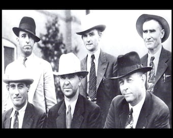 May include: Black and white photo of six men wearing hats. The men are standing in a row, and they are all looking at the camera. They are wearing suits and ties.
