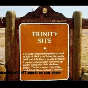 Könnte beinhalten: Ein braunes Holzschild mit dem Text "OFFICIAL SCENIC HISTORIC MARKER" und "TRINITY SITE". Das Schild beschreibt den Trinity Site, an dem am 16. Juli 1945 die erste Atombombe der Welt gezündet wurde.
