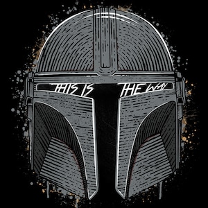 May include: A black and white illustration of a Mandalorian helmet with the text "This is the way" across the visor. The helmet is surrounded by a splatter of paint.