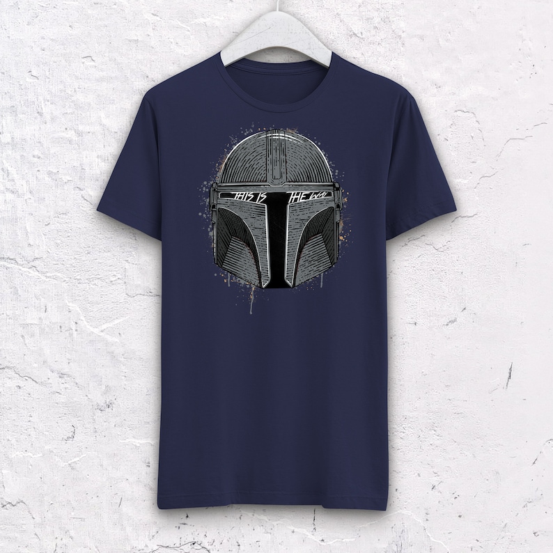 May include: A navy blue t-shirt with a white graphic of a Mandalorian helmet with the text "This is the way" on it.