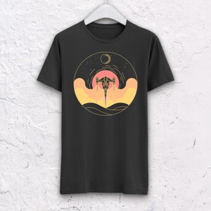 May include: Black t-shirt with a graphic of a spaceship flying through a sunset with a crescent moon in the background.