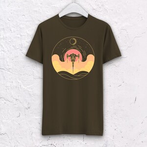 May include: A brown t-shirt with a graphic of a spaceship flying through a sunset with a crescent moon in the background.