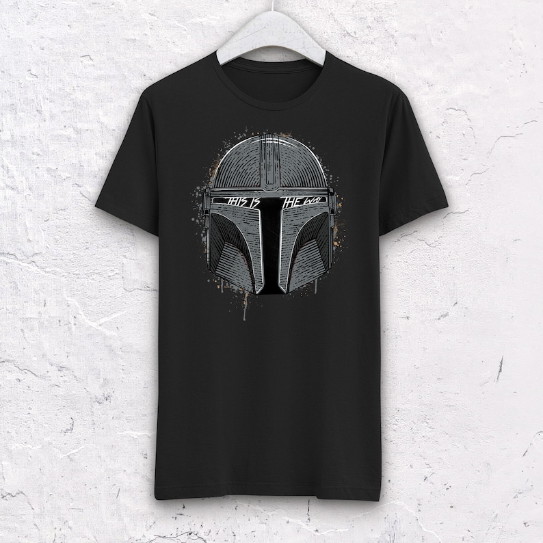 May include: Black t-shirt with a white and gray graphic of a Mandalorian helmet with the text "This is the way" on it.