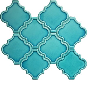 Puede incluir: Un conjunto de azulejos de cerámica azul turquesa con un diseño de trébol de cuatro hojas. Los azulejos están dispuestos en un patrón escalonado.