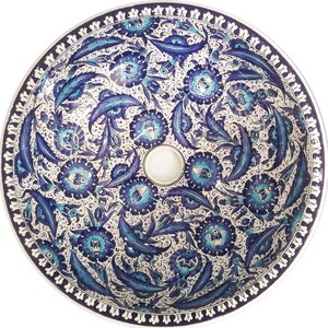 May include: A white ceramic sink with a blue and turquoise floral pattern. The sink is round and has a decorative border.