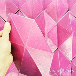 May include: Pink geometric ceramic tiles with a textured surface. The tiles are arranged in a pattern and have a glossy finish. The tiles are made by Vista Tiles True Terrazzo.