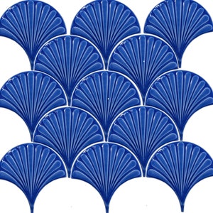 Puede incluir: Un conjunto de 12 azulejos de cerámica azules en forma de abanico. Los azulejos tienen un diseño en relieve y son perfectos para crear un salpicadero o una pared de acento único y elegante.