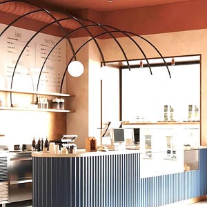 May include: Interior shot of a cafe with a curved counter featuring vertical blue and white panels, accented with gold trim. The ceiling is a warm terracotta color, and the design includes a menu board and decorative lighting. The Vista Tiles logo is visible.