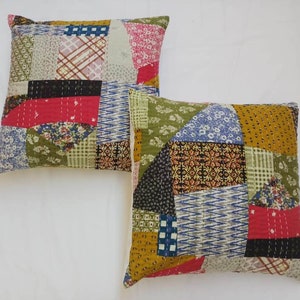 May include: Two square patchwork throw pillows with a variety of colorful fabrics and patterns. The pillows are made of cotton and have a quilted design.