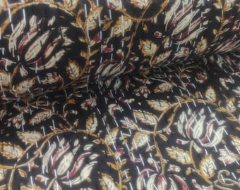 May include: A dark-colored quilt with a repeating pattern of stylized leaves and vines in shades of beige, brown, and red. The quilt is stitched with white thread, creating a textured surface. The overall design is a floral pattern.