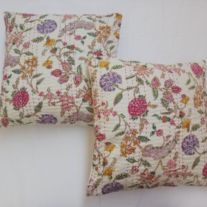 May include: Two white cotton pillow covers with a floral print in shades of pink, purple, yellow, and green. The floral pattern features delicate flowers and leaves on a white background.