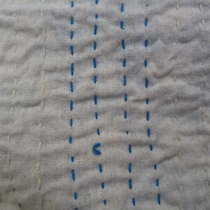 May include: White fabric with blue stitching in a straight line pattern.