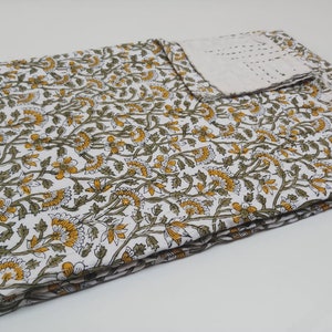 May include: White cotton fabric with a floral pattern in shades of yellow and green. The fabric is folded in thirds and has a white border.