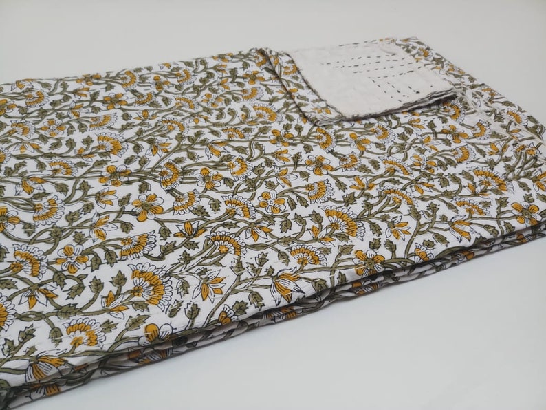 May include: White cotton fabric with a floral pattern in shades of yellow and green. The fabric is folded in thirds and has a white border.
