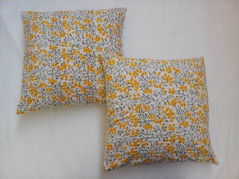 May include: Two white cotton pillow covers with a yellow floral pattern. The pillow covers have a quilted texture and are perfect for adding a touch of color and pattern to your home decor.