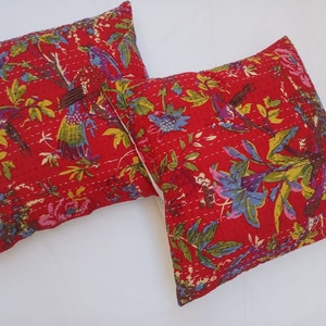 May include: Two red cotton pillow covers with a floral and bird print. The pillow covers are quilted and have a white background.