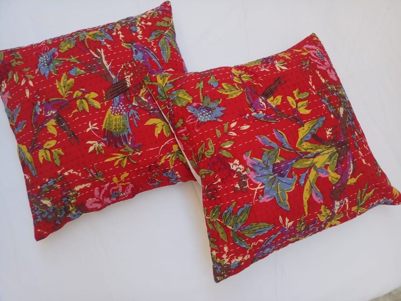 May include: Two red cotton pillow covers with a floral and bird print. The pillow covers are quilted and have a white background.