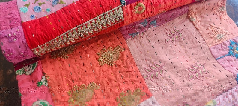 Pode incluir: Uma colcha de retalhos com uma variedade de cores e texturas. A colcha &eacute; feita de diferentes tecidos, incluindo rosa, vermelho e laranja. A colcha &eacute; decorada com bordados e lantejoulas.