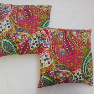 May include: Two pink and white paisley patterned throw pillows with green, blue, and orange accents.
