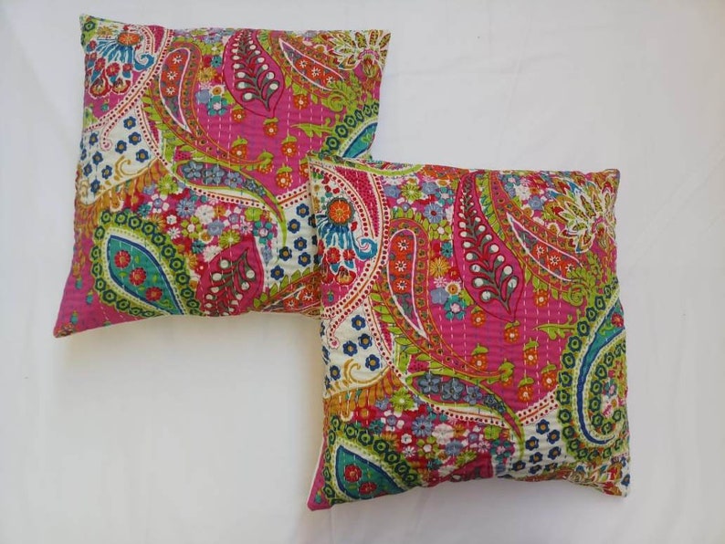 May include: Two pink and white paisley patterned throw pillows with green, blue, and orange accents.