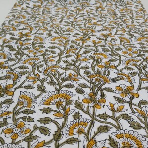 May include: White cotton fabric with a repeating pattern of yellow and green flowers. The fabric is perfect for quilting, sewing, or crafting.