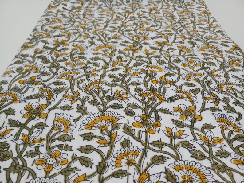 May include: White cotton fabric with a repeating pattern of yellow and green flowers. The fabric is perfect for quilting, sewing, or crafting.