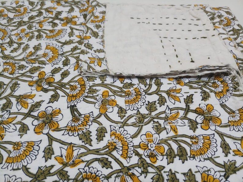 May include: White cotton kantha quilt with a floral pattern in shades of yellow and green. The quilt is hand-stitched and has a rustic, vintage look.