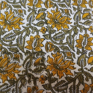 May include: White fabric with a repeating pattern of yellow and green floral designs. The fabric has a subtle texture.