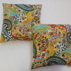 May include: Two decorative throw pillows with a paisley and floral pattern in shades of blue, green, yellow, red, and pink on a cream background.