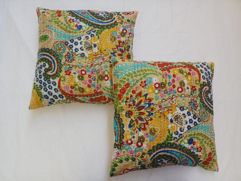 May include: Two decorative throw pillows with a paisley and floral pattern in shades of blue, green, yellow, red, and pink on a cream background.