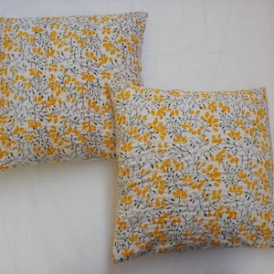 May include: Two white cotton pillow covers with a yellow floral pattern. The pillows are quilted and have a subtle texture.