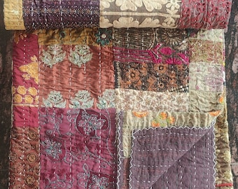 May include: A patchwork quilt with a variety of colors and patterns, including brown, red, gold, and white. The quilt is made of different fabrics and textures, and it has a unique, handmade look.