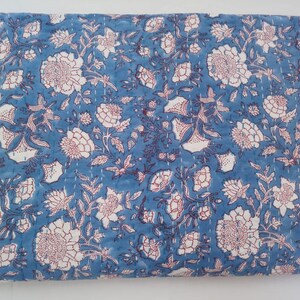 May include: A blue cotton quilt with a white and red floral pattern. The quilt is hand-stitched and has a traditional Indian design.